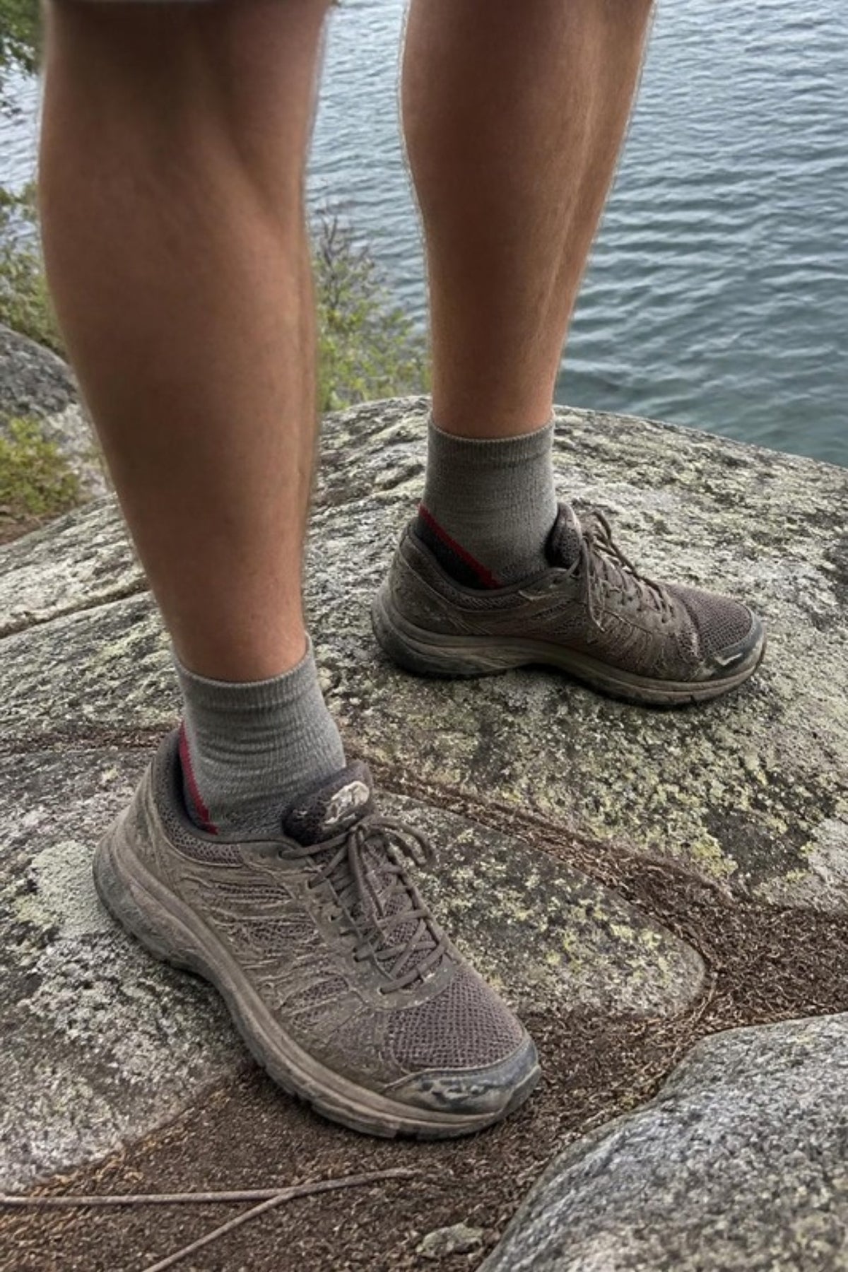 Darn Tough Light Hiker Quarter Lightweight Hiking Socks in Taupe worn with trail runners on a lakeside rock, low-profile merino socks for summer hikes, trail runs and everyday sneakers, guaranteed for life