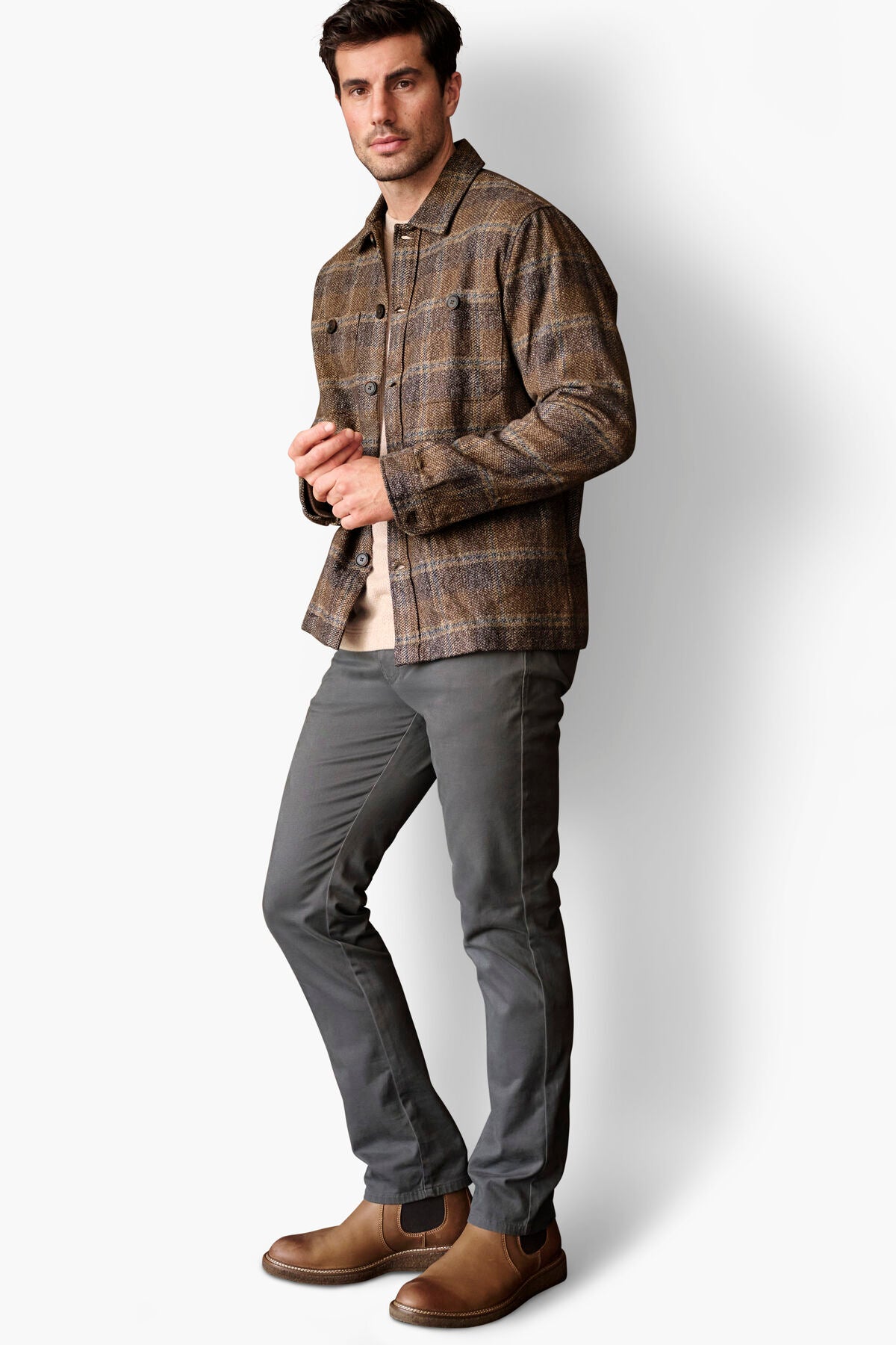 Full-length view of the Johnston & Murphy Marled Plaid Shirt Jacket in Brown/Navy styled with grey pants and Chelsea boots for an easy smart-casual look