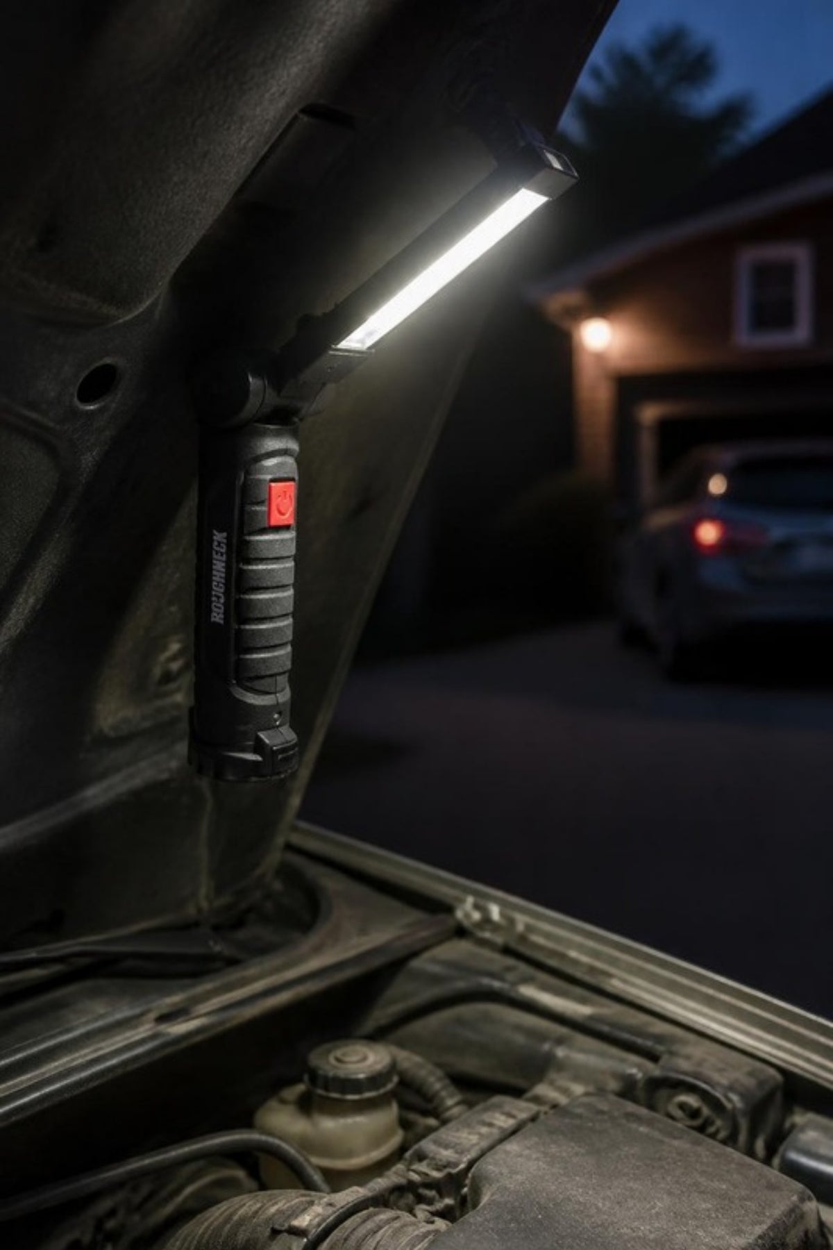 Roughneck magnetic work light stuck to the underside of a car hood, lighting up the engine bay hands-free for oil checks, jump starts and evening repairs in the driveway, a useful gift for anyone who works on their own car