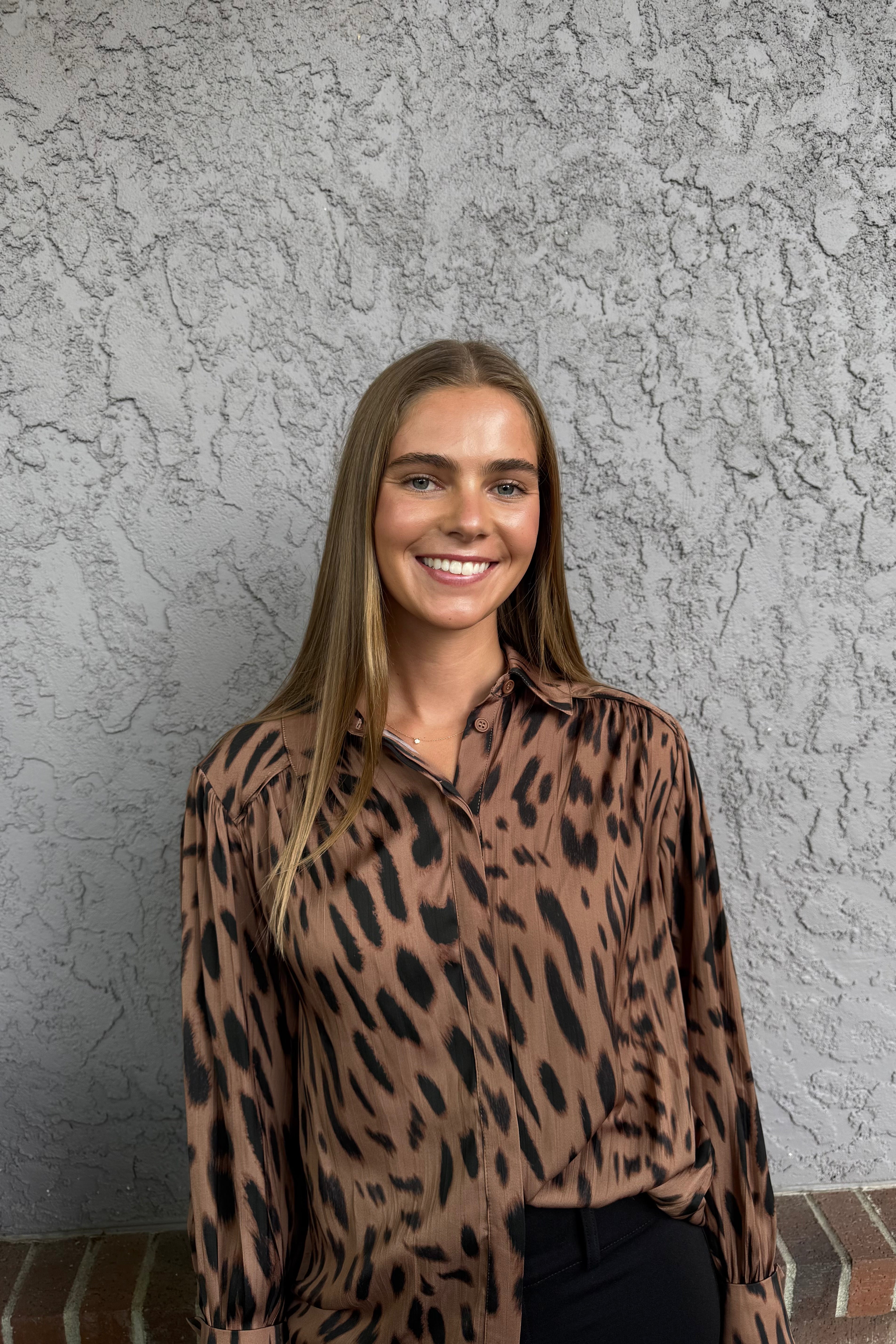 The Colette Top is a versatile addition to any wardrobe. Made from a crinkle sateen fabric, this blouse features a spread collar, long sleeves with single button cuffs, and a relaxed fit. The button front and pleat detail on the back add subtle touches of style.