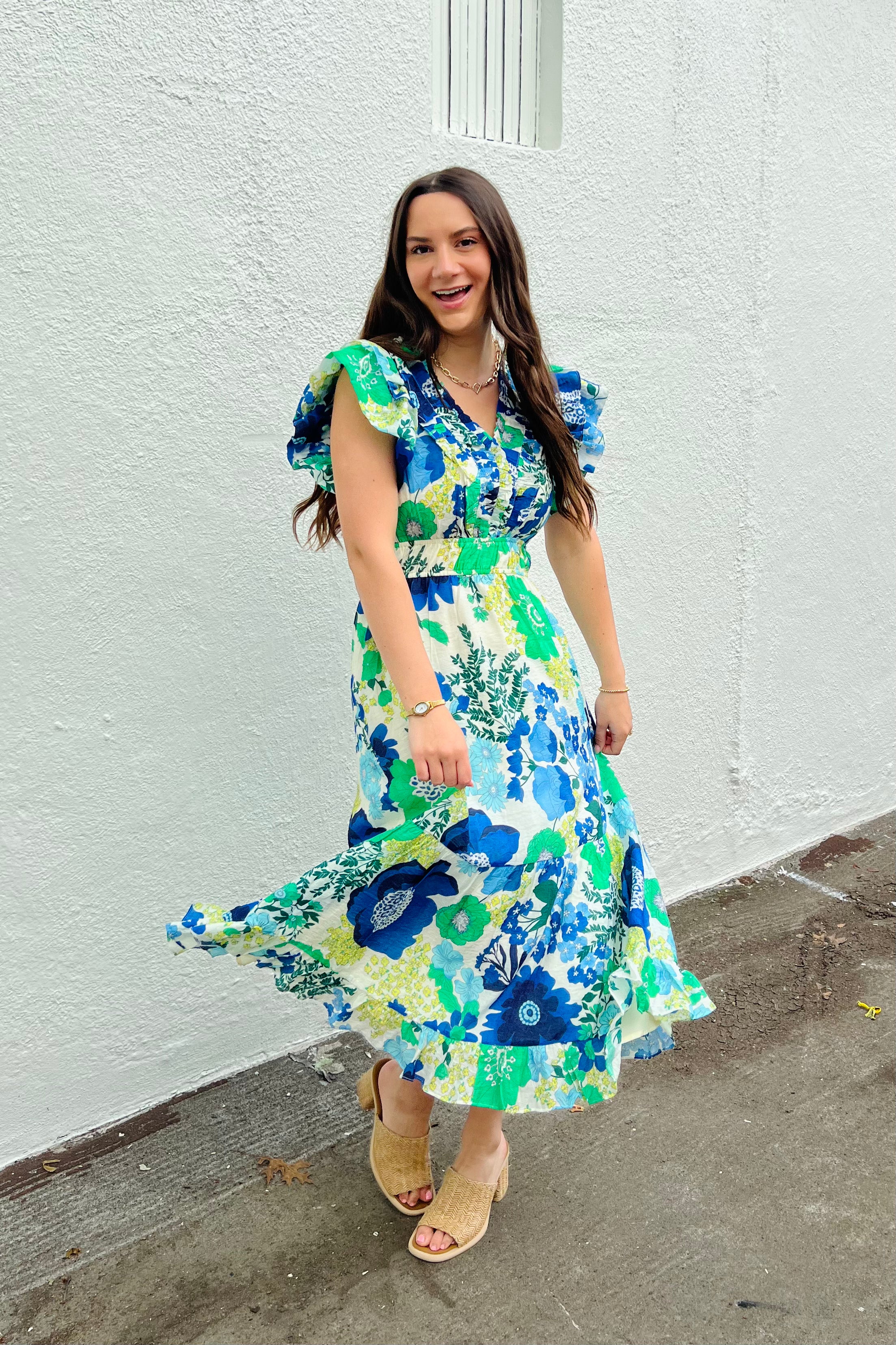 Woman in a floral dress standing against a white wall