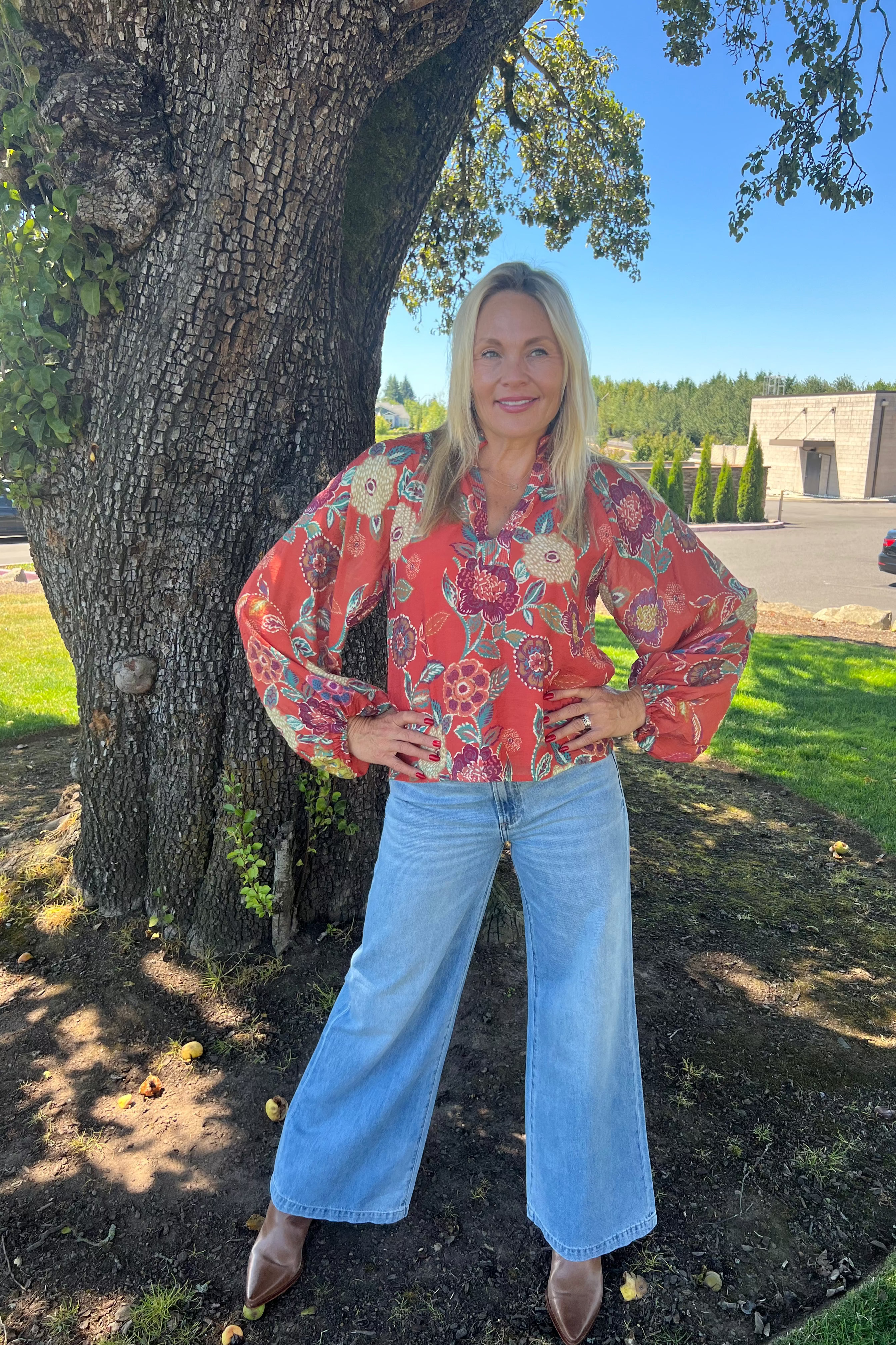 This blouse features a pleated collar, floral pattern, a split neckline with delicate stitching, and gathered sleeves for a refined look.