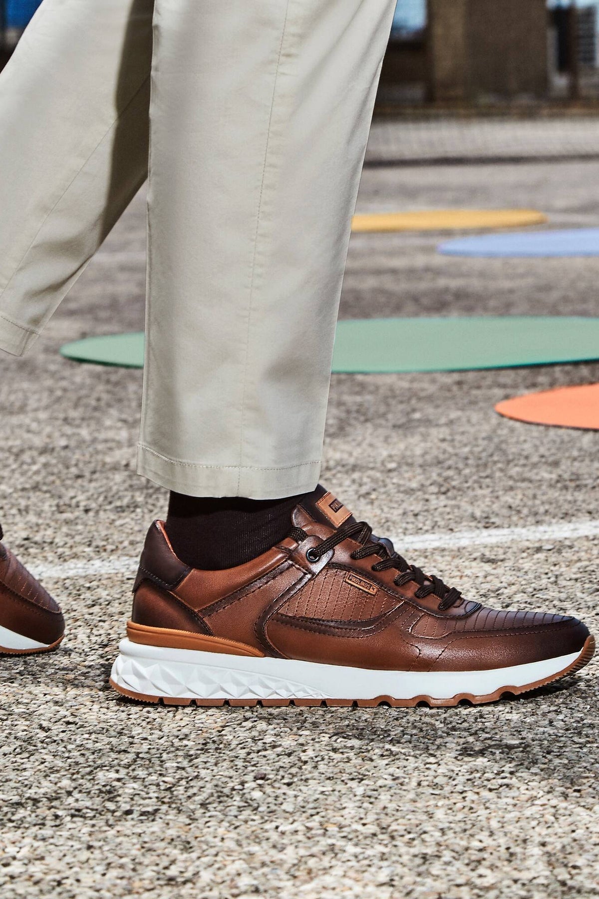 Pikolinos Aranda Sneaker in Cuero brown leather with a chunky white sole, worn with cream chinos outdoors, a comfortable leather sneaker for city walking, travel, casual Fridays and weekend errands