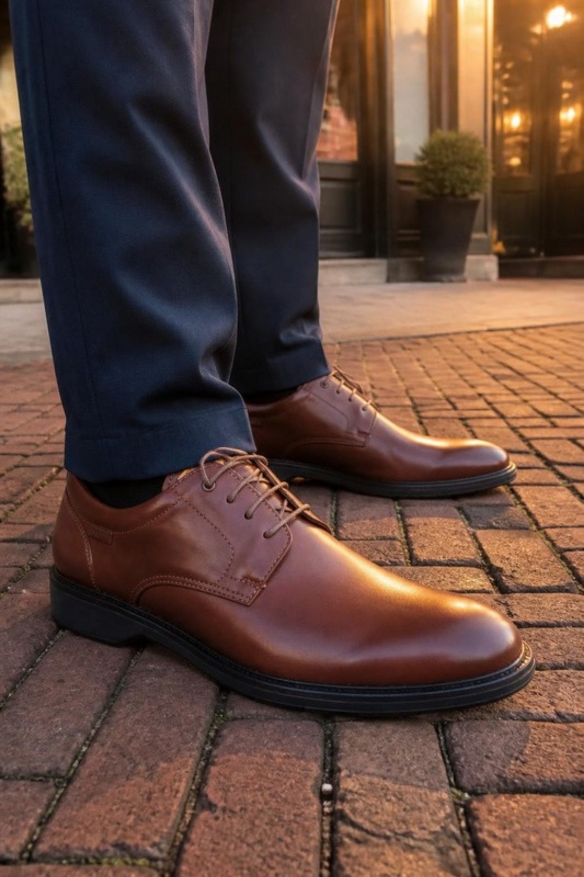 Pikolinos Carlet lace-up in Brandy brown calfskin leather with a lightweight sole, worn with navy suit trousers on a brick street at golden hour, a comfortable, versatile dress shoe for the office, weddings, dinners out and dressing up chinos or jeans