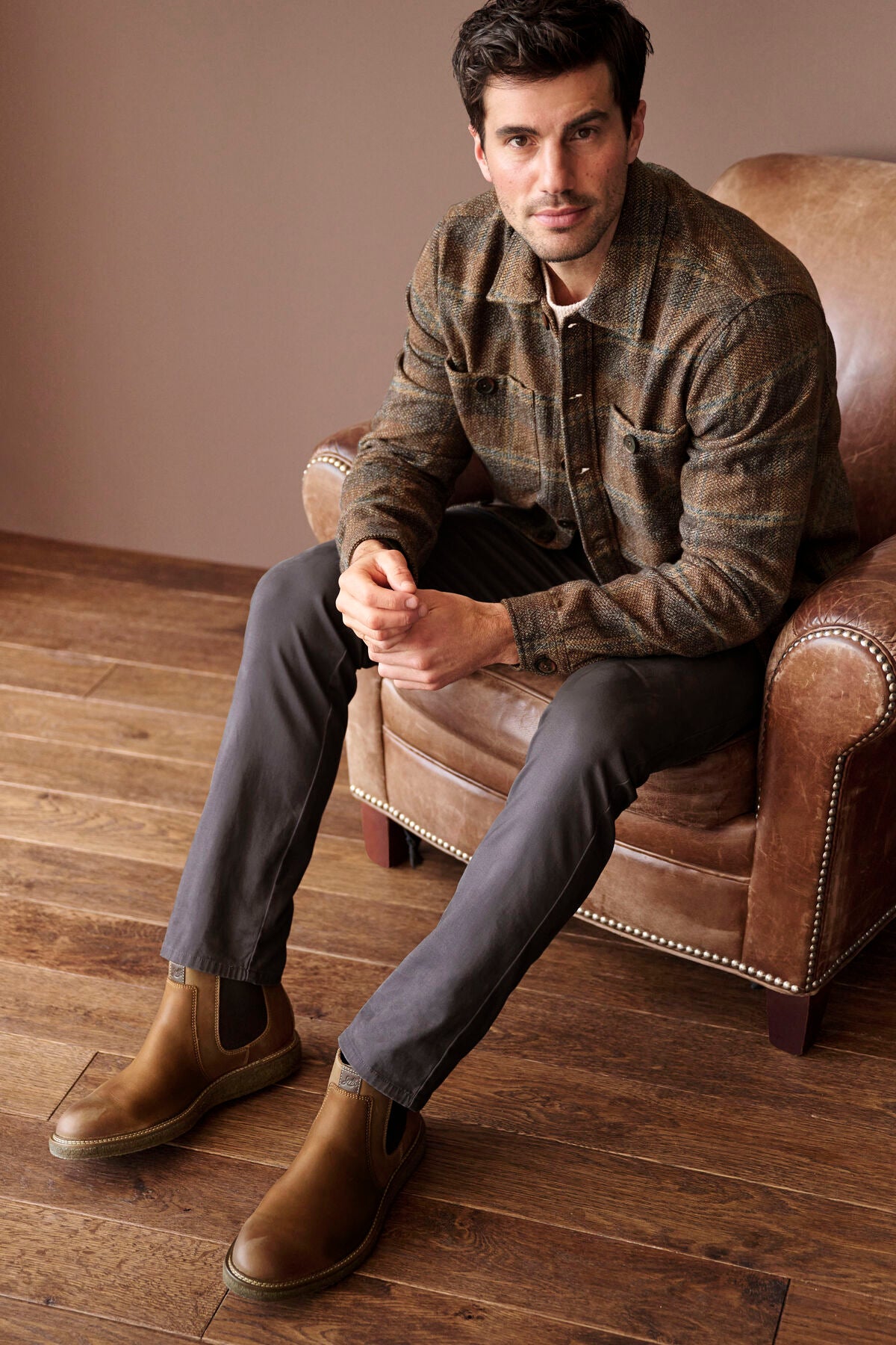 Man wearing the Johnston & Murphy Marled Plaid Shirt Jacket in Brown/Navy seated in a leather club chair, a warm brushed-cotton layer for fall weekends, casual Fridays and dinners out