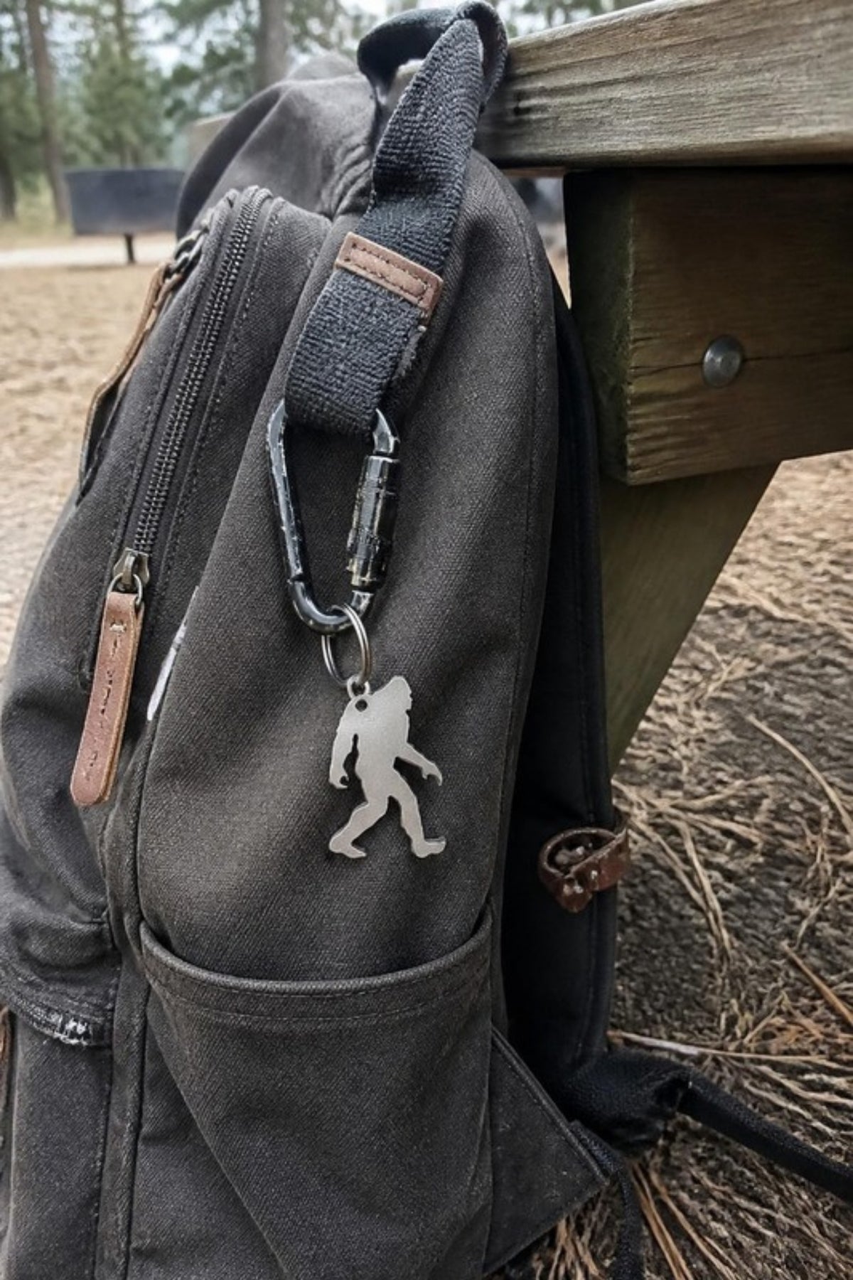 Paradise Cay Publications Micro Squatch keychain opener clipped to a backpack at camp, a tiny stainless steel Bigfoot bottle opener and carabiner for keys, packs and everyday carry, and a perfect little gift
