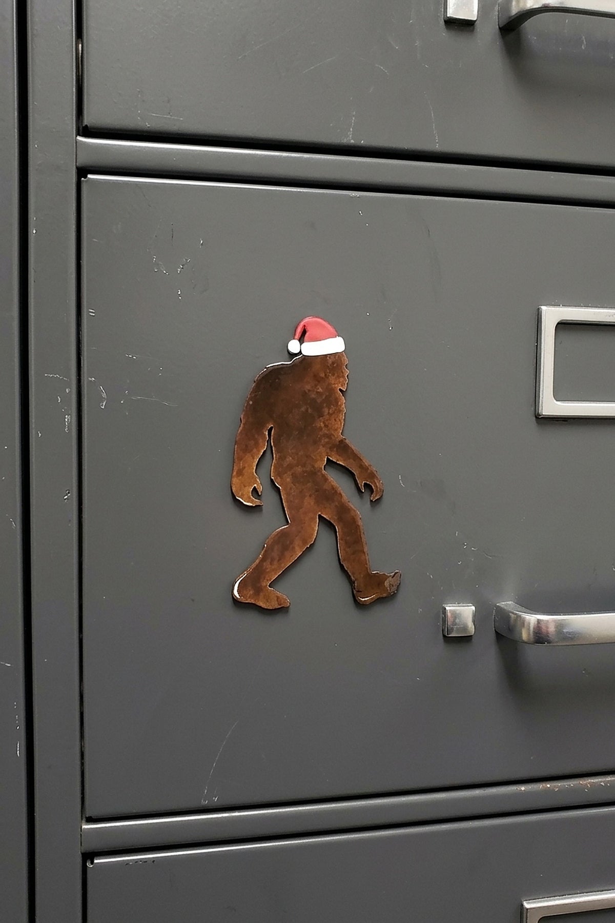 Paradise Cay Publications Santa Bigfoot magnet on a file cabinet, a holiday Bigfoot magnet that adds cheer to the office, garage or kitchen and makes an easy Christmas gift