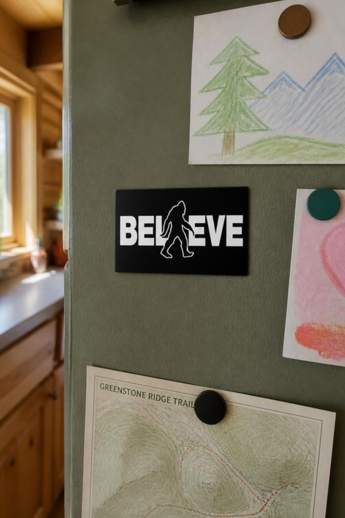 Signs 4 Fun Sasquatch Believe magnet on the fridge next to kids' drawings and a trail map, a small Bigfoot gift for the kitchen, toolbox or locker and an easy stocking stuffer