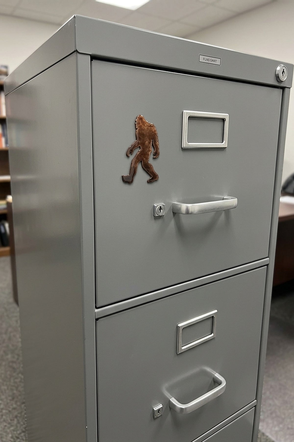 Paradise Cay Publications Walking Bigfoot large magnet on a grey file cabinet, a statement Bigfoot magnet for the office, shop or garage